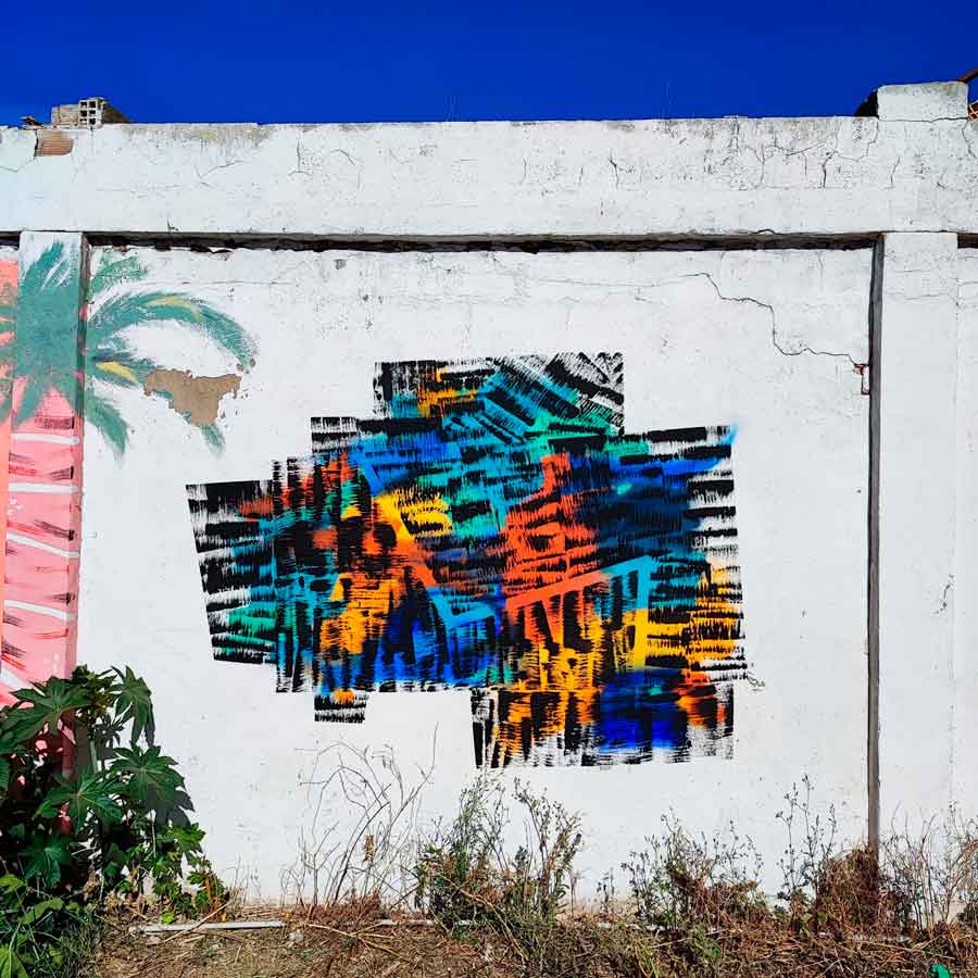 Artista urbano pintando una pared durante jornadas de puertas abiertas de la escuela valenciana de surf Supskull